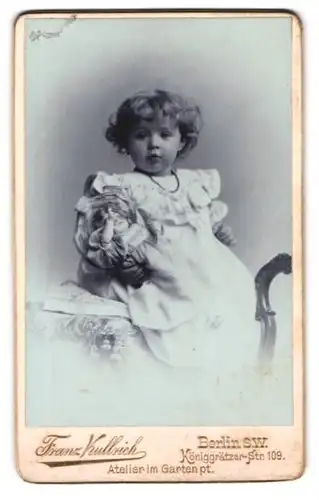 Fotografie Franz Kullrich, Berlin, Königgrätzer-Str. 109, kleines Mädchen mit ihrer Puppe sitzt auf dem Tisch