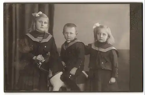 Fotografie Georg Krehn, Fürth i. Bayern, Portrait drei Geschwister in Matrosenkleidern mit Schaukelpferd