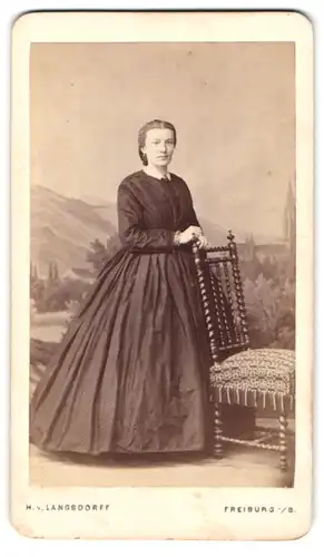 Fotografie H. v. Langsdorff, Freiburg i. B., elegante Dame im schwarzen Kleid vor Studiokulisse