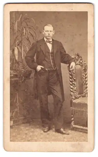 Fotografie C. T. Schultze, Querfurt, Herr im modischen Anzug lehnt lässig am Stuhl
