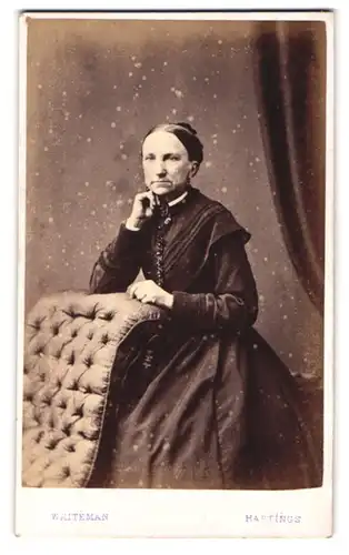 Fotografie E. Whiteman, Hastings, 52 High Street, Portrait betagte Dame mit Dutt im schwarzen Kleid