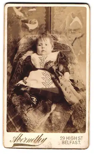 Fotografie Abernethy, Belfast, 29, High St., Süsses Kleinkind im Kleid sitzt auf Fell