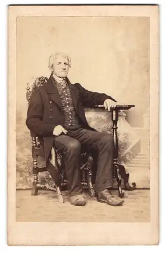 Fotografie Aug. Röthig, Ebersbach, Portrait älterer Herr im Anzug mit gestreifter Weste sitzend im Atelier