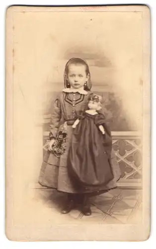 Fotografie W. Grigoleit, Rathenow, niedliches kleines Mädchen im Kleid mit ihrer Puppe in der Hand