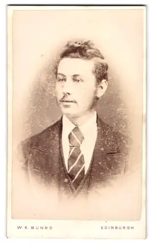 Fotografie W. K. Munro, Edinburgh, Pitt Street 58, Junger Mann mit ungebändigten Haaren und gestreifter Krawatte