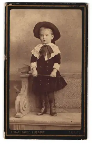 Fotografie Sebastianutti & Benque, Trieste, Hübsch gekleidetes Kind mit einem Stock