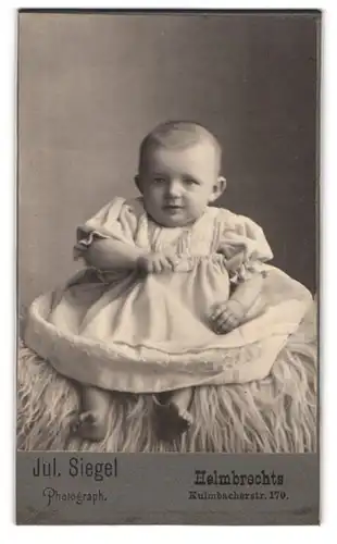 Fotografie Jul. Siegel, Helmbrechts, Kulmbacherstr. 170, Süsses Kleinkind im Kleid sitzt auf Fell