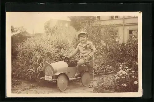 AK Knabe mit Spielzeugauto in einem Garten