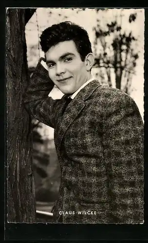 AK Schauspieler Claus Wilcke lehnt lässig an einem Baum