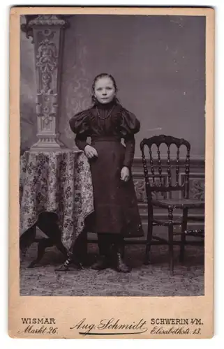 Fotografie Aug. Schmidt, Wismar, Markt 26, Portrait niedliches Mädchen im prachtvollen Kleid