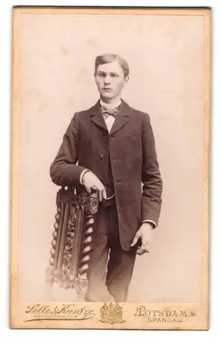 Fotografie Selle & Kuntze, Potsdam, Schwerdtfegerstr. 14, Portrait junger Mann im Anzug am Stuhl stehend
