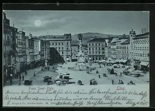 Mondschein-AK Linz, Franz Josef-Platz mit Geschäften und Denkmal