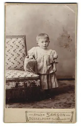 Fotografie Ateier Samson, Düsseldorf, Schadowstrasse 77, Kleinkind im niedlichen Kleidchen und fragendem Gesichtsausdruck