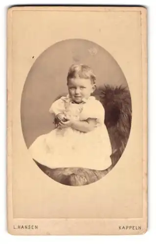 Fotografie L. Hansen, Kappeln, Kleinkind im Kleid auf Pelzdecke