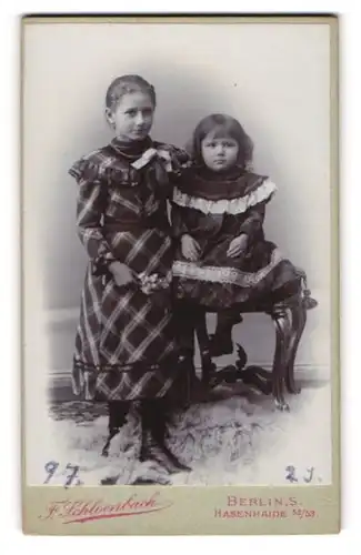 Fotografie F. Schloenbach, Berlin-S., Hasenheide 52-53, Junges Mädchen im karierten Kleid mit einem Kleinkind