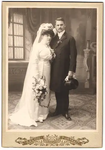 Fotografie unbekannter Fotograf und Ort, Brautpaar im Hochzeitskleid und Anzug mit Zylinder posiert im Atelier