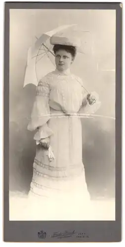 Fotografie Friedr. Haack, Jena, Portrait junge Dame im schneeweissen Kleid mit Sonnenschirm und Pelzmütze