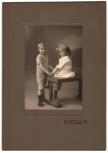 Fotografie Herm. Jursch, Nürnberg, Portrait zwei niedliche Kindern im weissen Kleid mit Haarschleife halten Händche, 2.WK