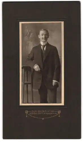 Fotografie Aug. Baumeister, Düsseldorf, junger Mann im dunklen Anzug mit Moustache