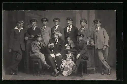 AK Studentengruppe mit Mützen, versammelt um Student mit Fellmütze und Degen, Wappen