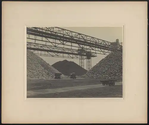 Fotografie W. Kein, Hamburg, Ansicht Lübeck, Erz - und Kohlelager mit Förderbrücke des Hochofenwerkes am Hafen