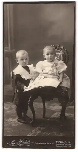 Fotografie Max Fischer, Berlin, Portrait zwei niedliche Kindern im schwarzen und weissen Kleidchen lesen eine Zeitung