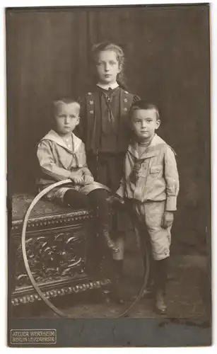 Fotografie Atelier Wertheim, Berlin, drei Kinder in Anzrügen und im Kleid mit Reifen posieren im Atelier