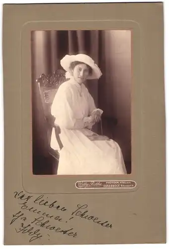 Fotografie Willy Bothe, Osnabrück, junge Frau im weissen Sommerkleid mit Hut und Handtasche posiert sitzend