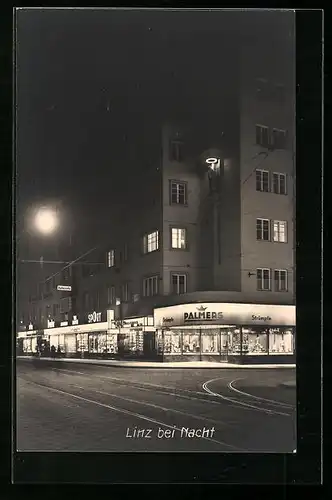 AK Linz a. D., Linz bei Nacht, Strassenpartie mit Geschäft