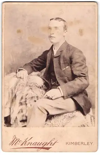 Fotografie Mc Knaught, Kimberley, Woodley St., Junger Herr in Anzugjacke sitzt auf Fell