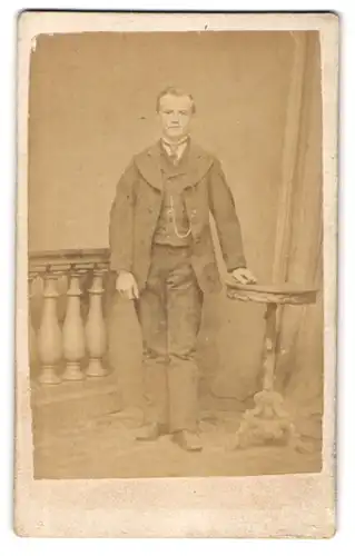 Fotografie Hermann Ramm, Hannover, Tellerstrasse 57, Junger Mann im bürgerlichen Anzug neben einem Tisch posierend