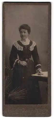 Fotografie unbekannter Fotograf und Ort, junge Frau im schwarzen Kleid mit weisser Spitze und Halskette