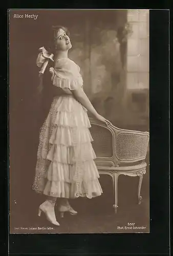 AK Schauspielerin Alice Hechy mit Haarschleife im Kleid am Stuhl stehend
