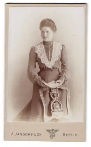 Fotografie A. Jandorf & Co., Berlin, C. Spittelmarkt 16 /17, Dame mit Buch in der Hand an Stuhl lehnend