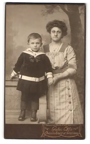 Fotografie Gebr. Otto, Oranienburg, Mutter nebst Sohn im Matrosenanzug vor Studiokulisse