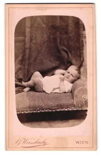 Fotografie H. Weissbach, Wien, Mariahilferstrasse 54, Liegendes Kleinkind mit angezogenen Beinen