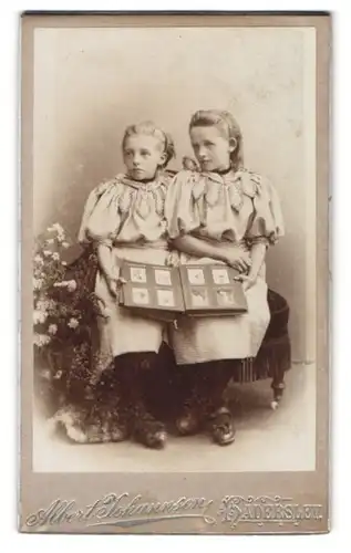 Fotografie Albert Johannsen, Haderslev, Zwei Mädchen in identischen Kleidern mit Fotoalbum