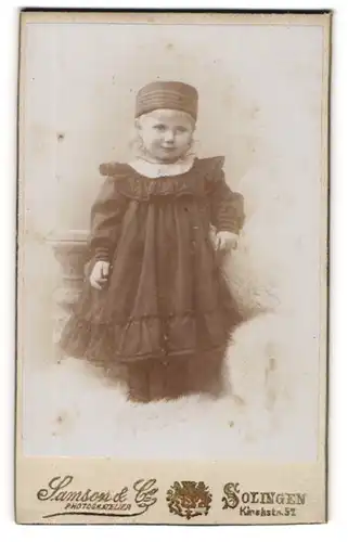 Fotografie Samson & Co., Solingen, Kirchstr. 57, Mädchen mit Mütze im Kleidchen