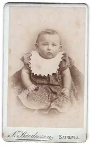 Fotografie N. Brodersen, Satrup i. A., Baby mit Latz im karierten Kleidchen