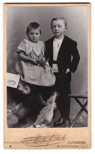 Fotografie M. Frölich, Flensburg, Norderhofenden 9, Kind mit kurzen Haaren im Kleidchen und Knabe im Anzug