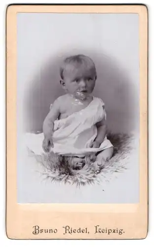 Fotografie Bruno Riedel, Leipzig, Baby im Strampelkleid auf einem Fell