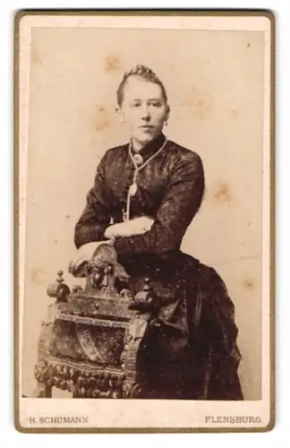 Fotografie H. Schumann, Flensburg, Holm 1, Frau mit Flechtfrisur und Brosche in tailliertem Kleid