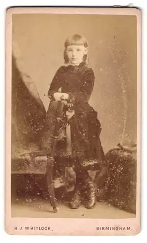 Fotografie H. J. Whitlock, Birmingham, 11. New Street, Niedliches kleines Mädchen posiert neben einem Stuhl