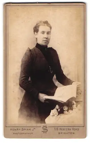 Fotografie H. Spink, Brighton, Western Road 109, Frau mit ernstem Blick im dunklen taillierten Kleid