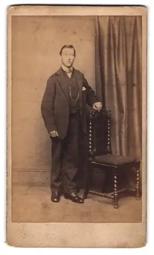 Fotografie unbekannter Fotograf und Ort, Mann im Anzug am Stuhl stehend