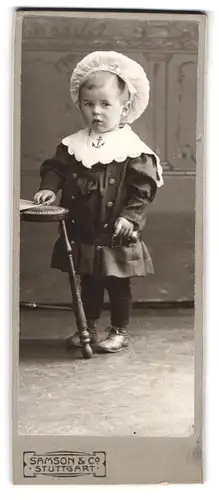 Fotografie Samson & Co., Stuttgart, Königstrasse 60, Kleiner Junge mit grosser weisser Mütze im Matrosenkleid