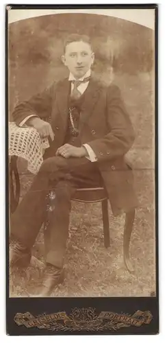 Fotografie unbekannter Fotograf und Ort, Junger Mann im eleganten Dreiteiler an einem Tischchen im Garten