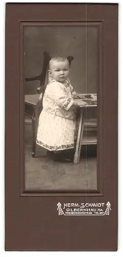 Fotografie Herm. Schmidt, Olbernhau, Freibergerstrasse 28, Kleinkind in hellen Kleidchen mit einem Bilderbuch