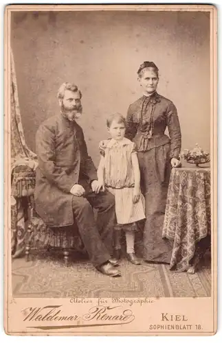 Fotografie Waldemar Renard, Kiel, Sophienblatt 18, Bärtiger Bürgerlicher mit Frau und kleinem Mädchen im Sonntagsstaat