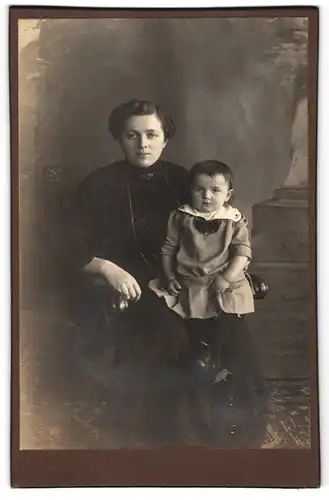 Fotografie unbekannter Fotograf und Ort, Mutter im schwarzen Kleid mit ihrem Kind auf dem Schoss, Mutterglück
